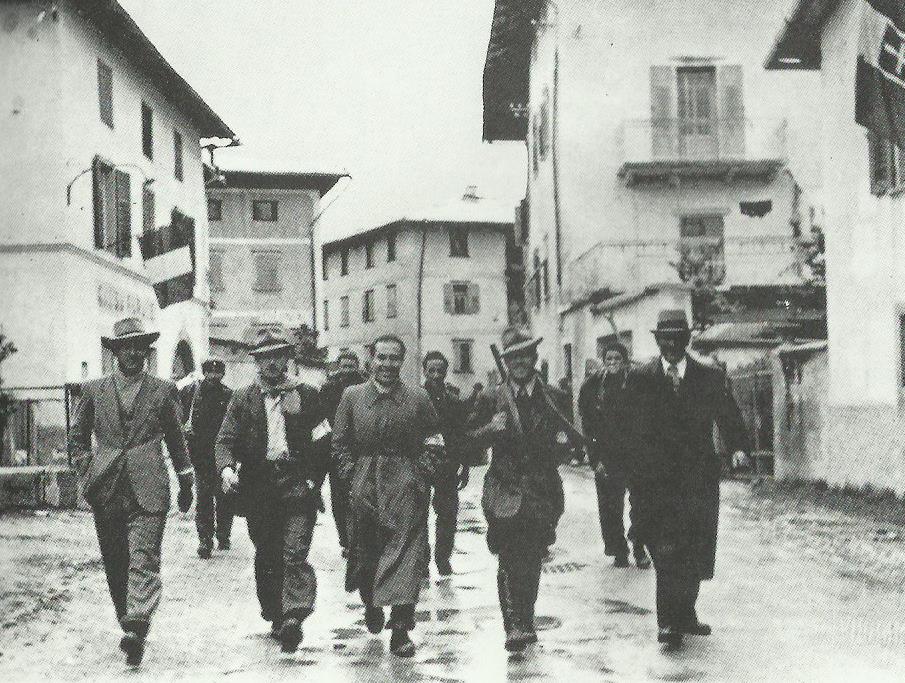 5 maggio1945: i comandanti del Comitato di Liberazione Nazionale della val di Non, con il tricolore al braccio, sfilano per la strada principale di Romeno