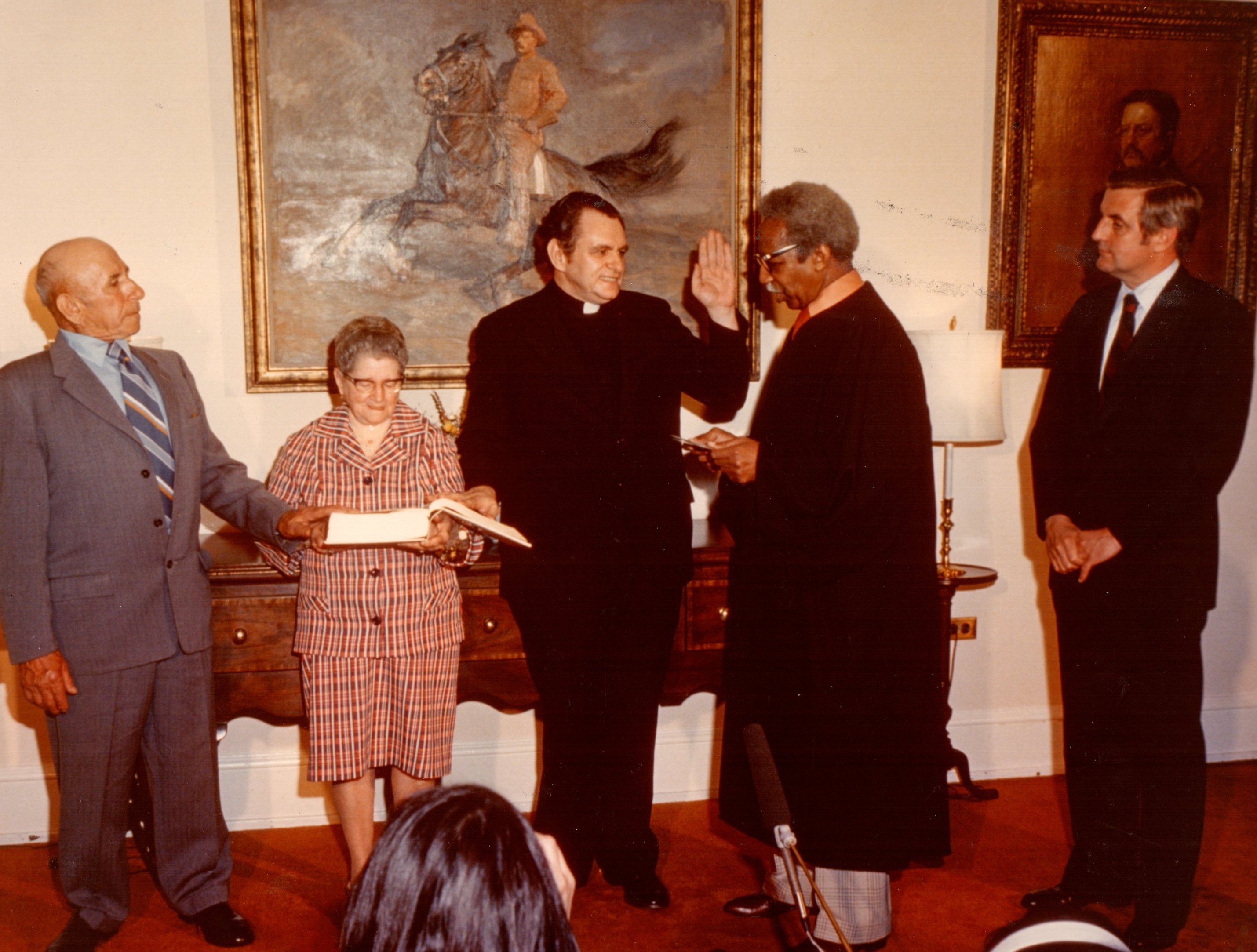 Mons. Baroni giura davanti al giudice della Corte Federale e al Vicepresidente Walter Mondale. A fianco i genitori di Geno