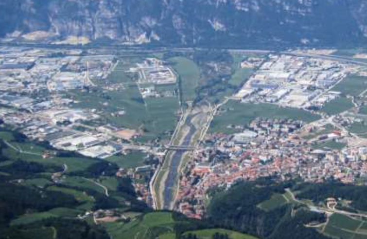 Foto aerea del torrente Avisio che sfocia nel fiume Adige attaccato alla montagna. In primo piano l’abitato di Lavis e sullo sfondo è visibile il lungo viadotto curvilineo della linea ferroviaria del Brennero (anno 2012)
